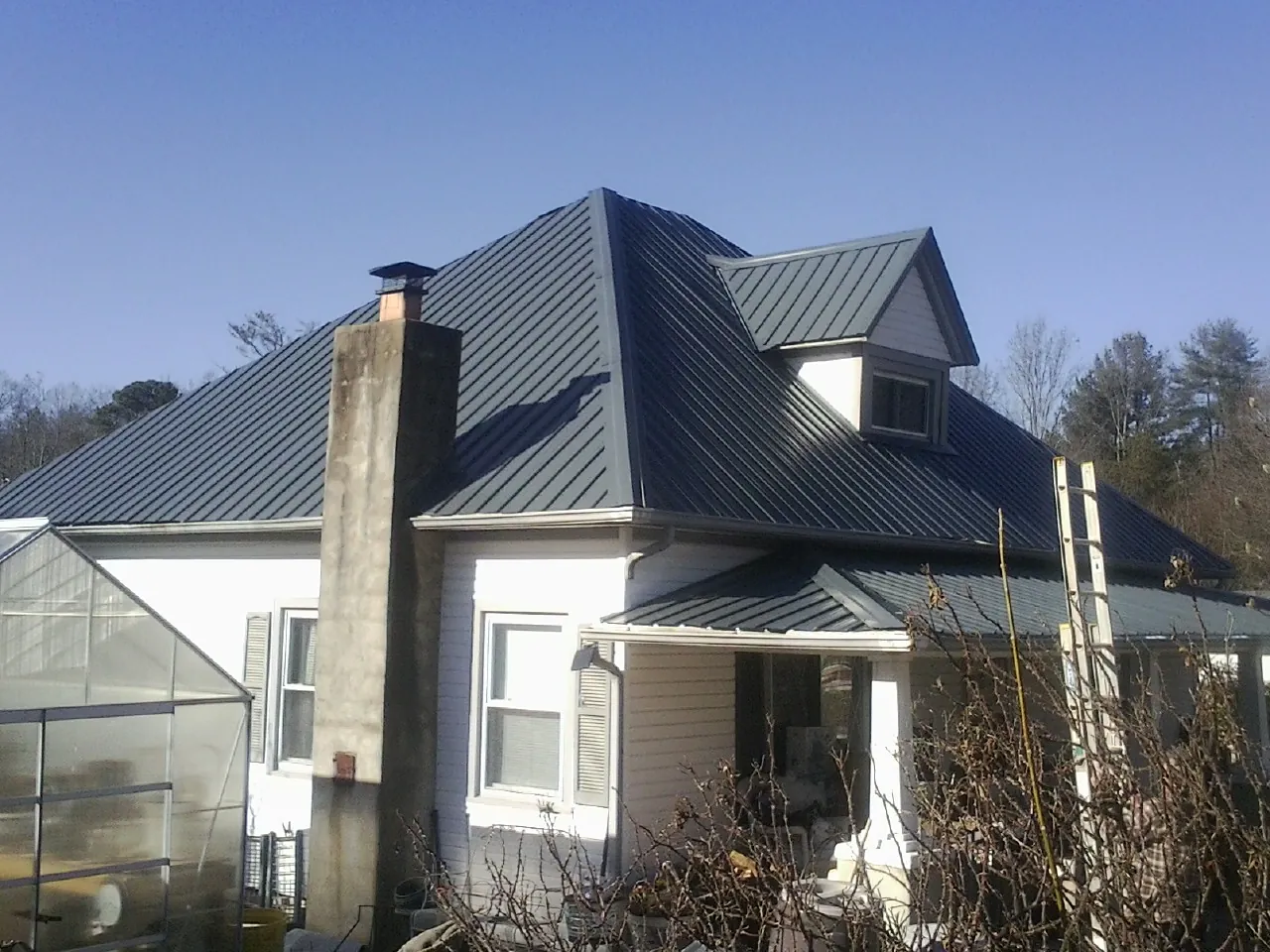 Dark blue standing seam metal roof on a white farmhouse with dormer — Slate & Tile Roof Repair by Roofing Brothers in San Gabriel