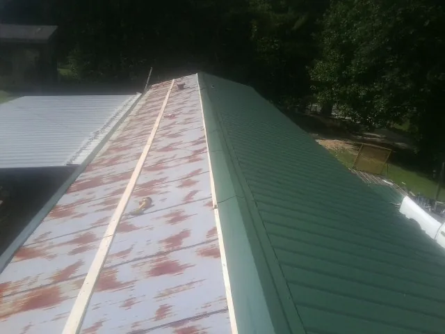 Old rusted panels beside newly installed green metal roofing — Wind Damage Roof Repair by Roofing Brothers in San Gabriel