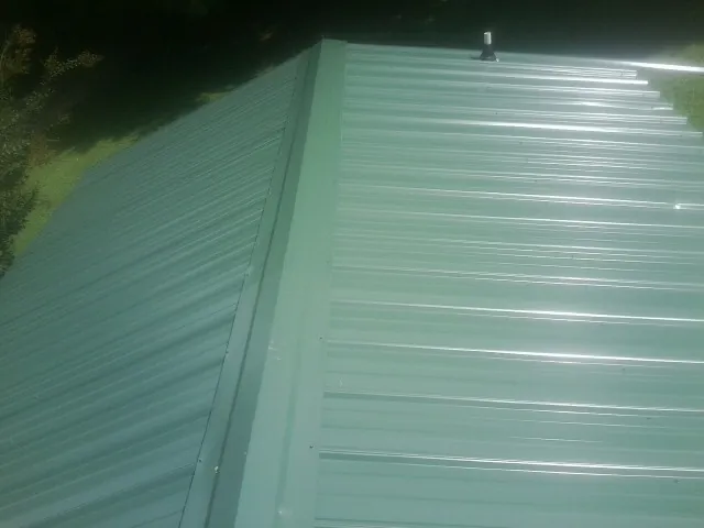 New green metal panels meeting at the ridge of a roof — Flat Roof Repair work by our crew in San Gabriel