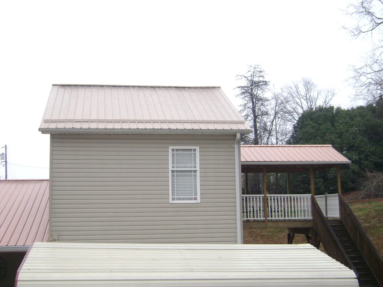 Tan metal roofs on a two story addition and attached porch, from a Roof Replacement job in San Gabriel