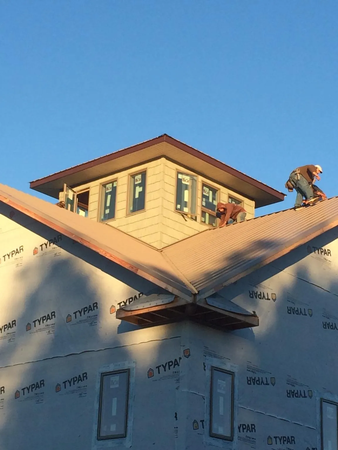 Roofers working around a rooftop cupola on a new metal roof at sunset — Roof Waterproofing in San Gabriel by Roofing Brothers